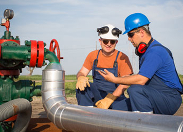 Technicians inspecting a pipeline valve assembly on site